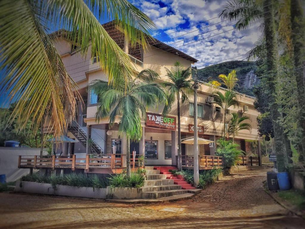 a building with palm trees in front of it at Pousada Fora do Ar TakeOFF in Alfredo Chaves