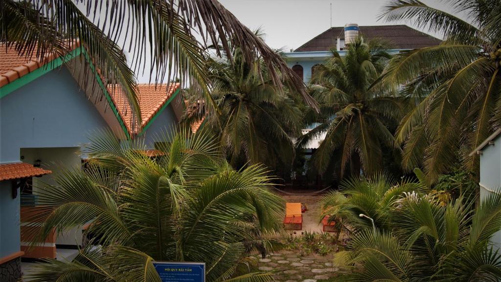 a group of palm trees in front of a building at Hong Di Guesthouse in Mui Ne