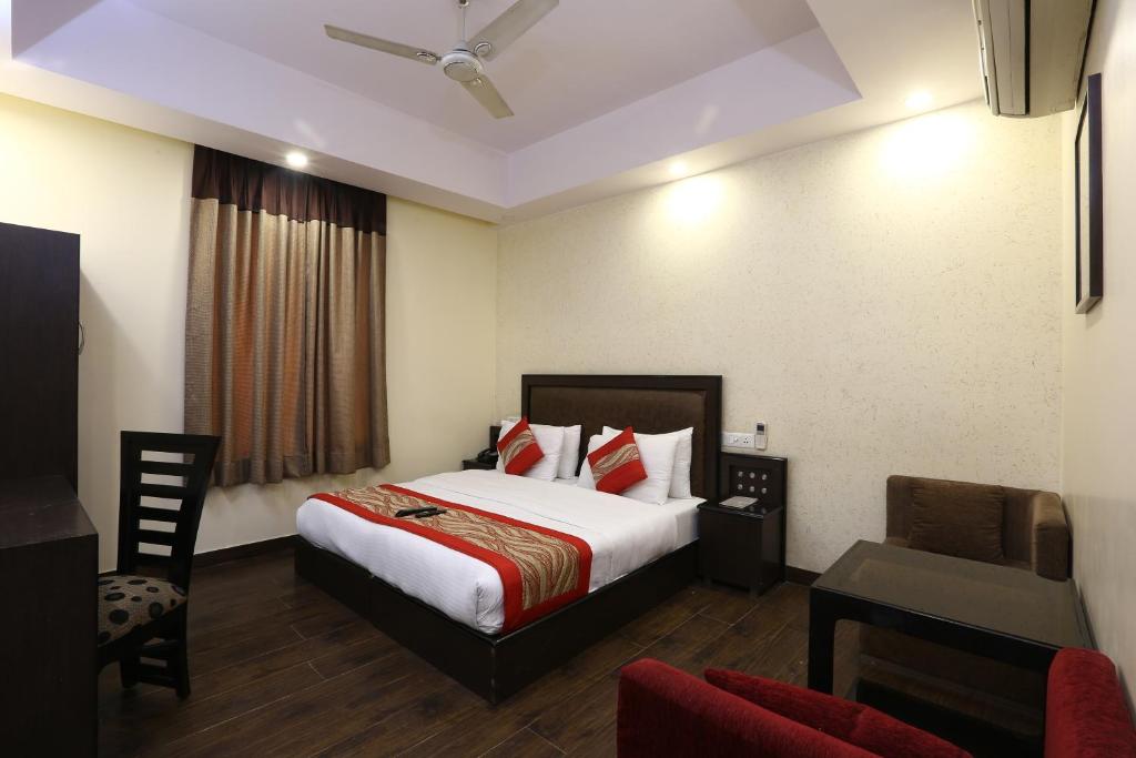 a hotel room with a bed and a chair and a desk at Hotel Kingston Park in New Delhi