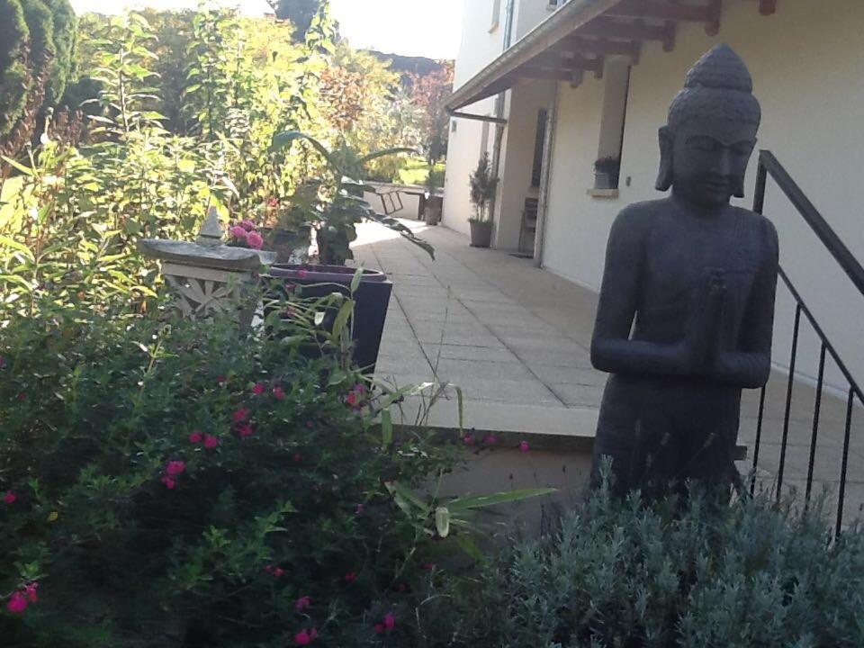 una estatua en un jardín frente a un edificio en Maison d'hôtes Les Coudreaux, en Rueil-Malmaison