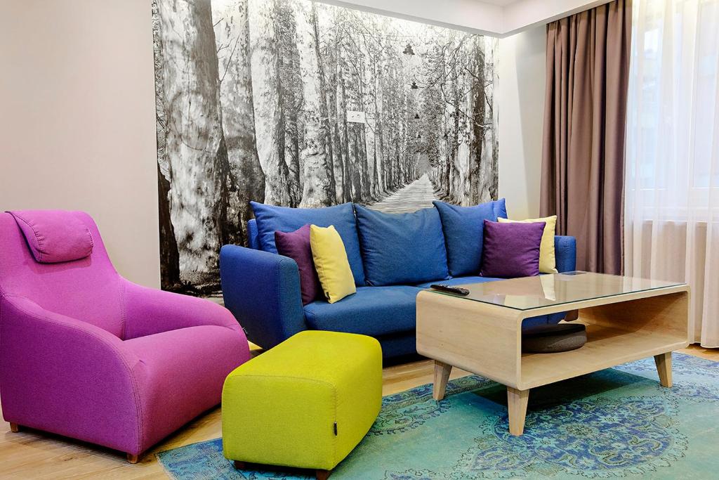 a living room with a blue couch and colorful chairs at City Center Apartment Sarajevo Accross BBI Shopping Mall in Sarajevo