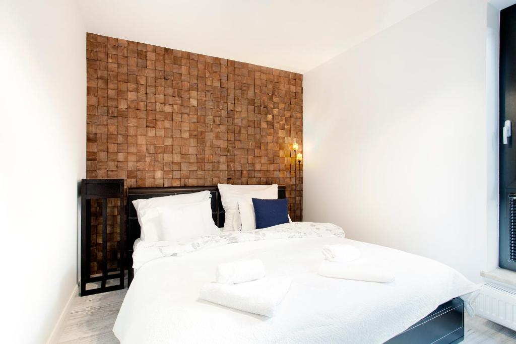 a bedroom with a white bed and a brick wall at Dream - Victoria Residence by OneApartments in Sopot