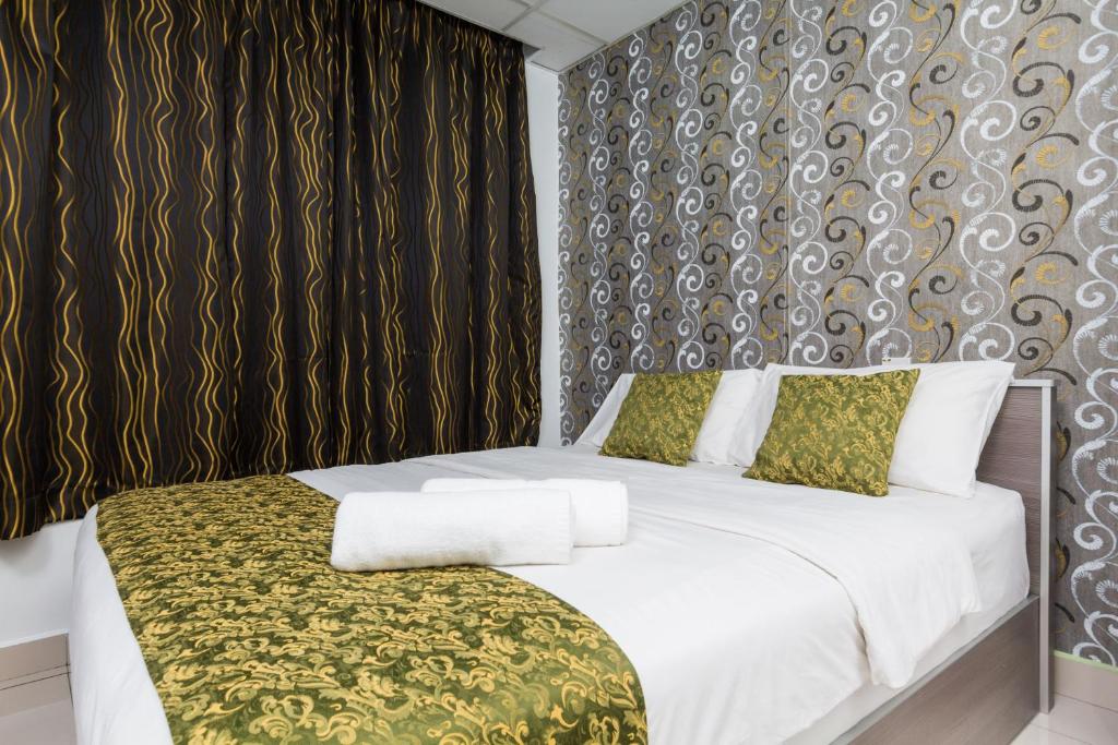 um quarto com uma cama branca e um cobertor verde em Lacomme Inn em Kuala Lumpur