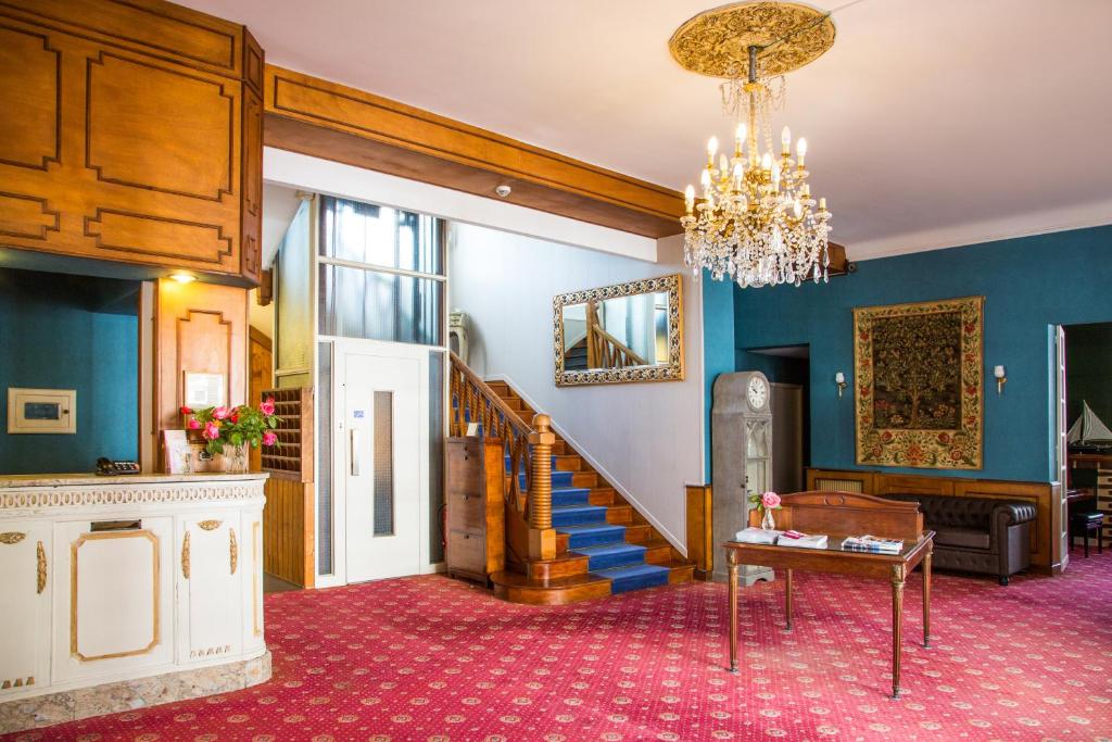 a living room with a staircase and a chandelier at Hostellerie de La Roseraie in Barbotan-les-Thermes