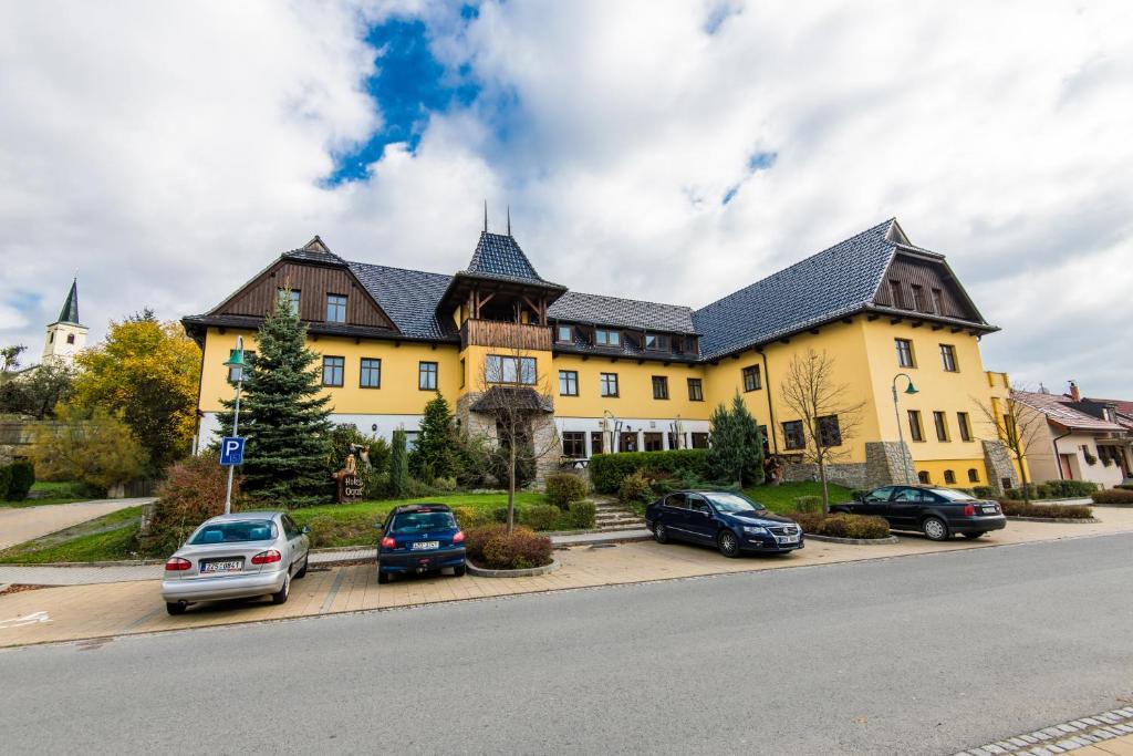 uma grande casa amarela com carros estacionados em frente em Valašský Hotel a Pivní lázně OGAR em Luhačovice