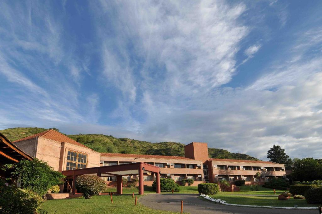 duży ceglany budynek z pochmurnym niebem w obiekcie Pinares del Cerro Resort & Suites w mieście Villa Carlos Paz