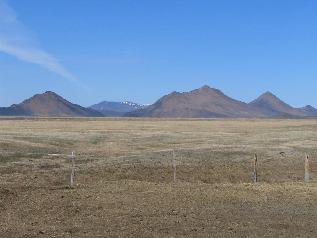 a fence in a field with mountains in the background at Fjalladýrð Guesthouse in Modrudalur