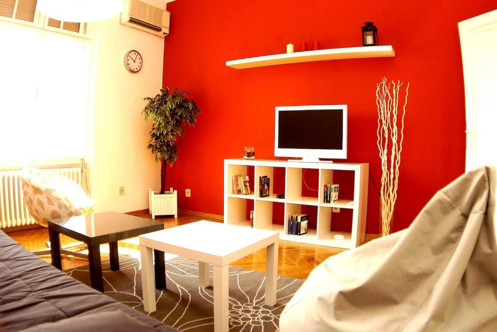 un soggiorno con una parete rossa e una TV di Bridge apartment a Belgrado