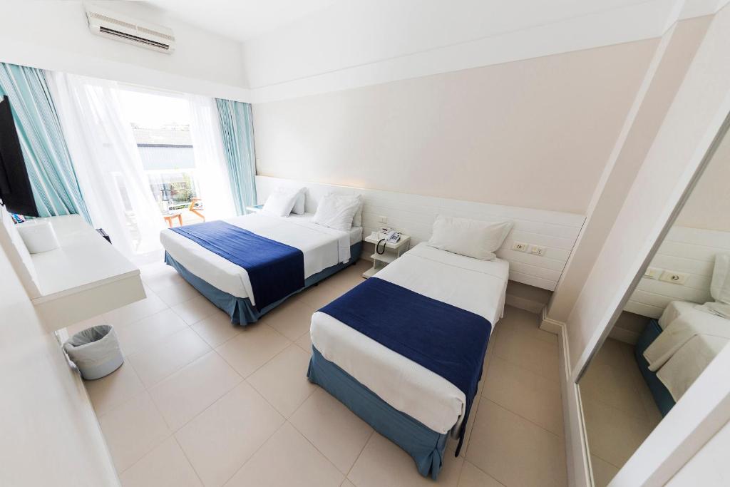 um quarto de hotel com duas camas e uma janela em The Falls Hotel no Guarujá