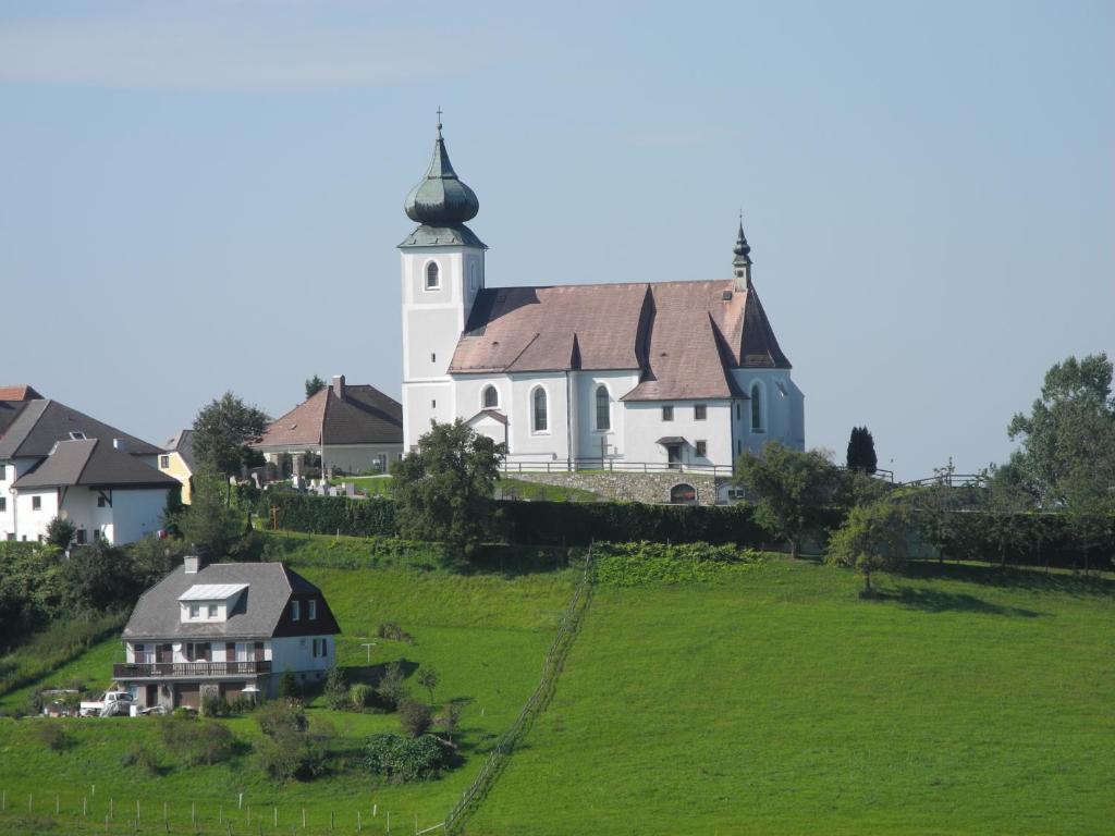 a white church with a tower on a green hill at Ferienwohnungen Kössl in Waidhofen an der Ybbs