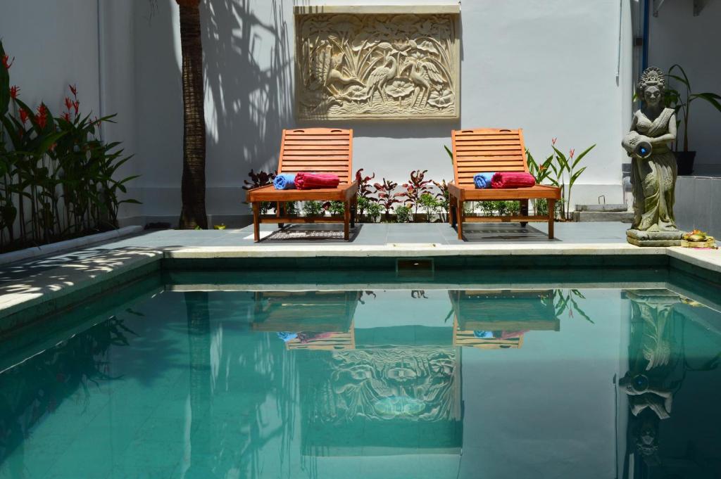 two chairs sitting next to a swimming pool at Askara Guest House & Hostel in Ubud