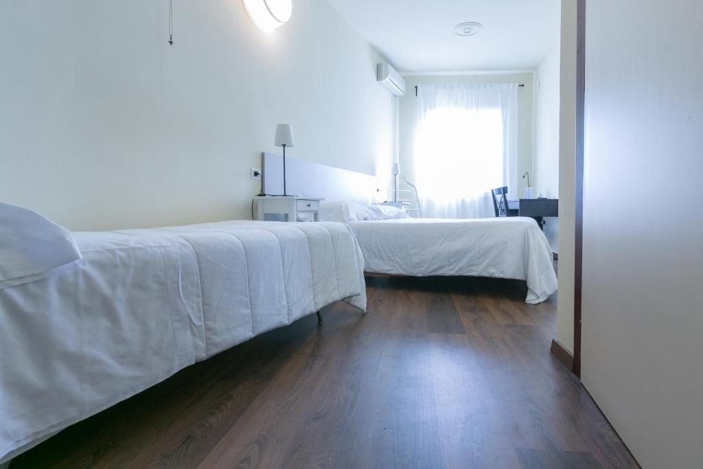 una camera da letto con un letto con lenzuola bianche e un pavimento in legno di Albergo Il Cochino a Montale