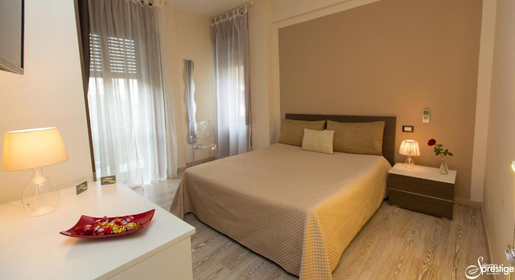 Salernoprestige b&b في ساليرنو: غرفة نوم مع سرير ووعاء من الزهور على طاولة