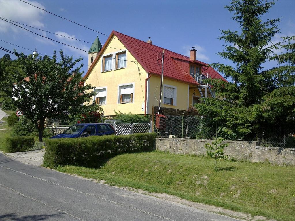 a yellow house with a red roof on a street at György Vendégház in Magyarpolány