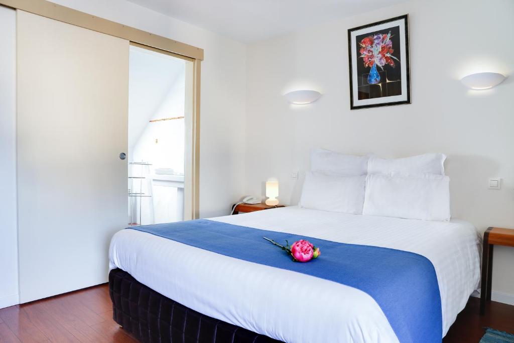ein Schlafzimmer mit einem großen Bett mit einer Blume darauf in der Unterkunft Hôtel Le Chevalier Gambette in Saint-Armel