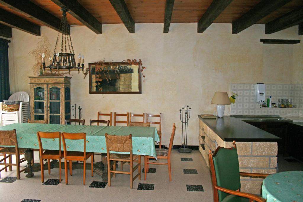 a dining room with a green table and chairs at Mas des Tours Chambre d'hôtes in Tornac