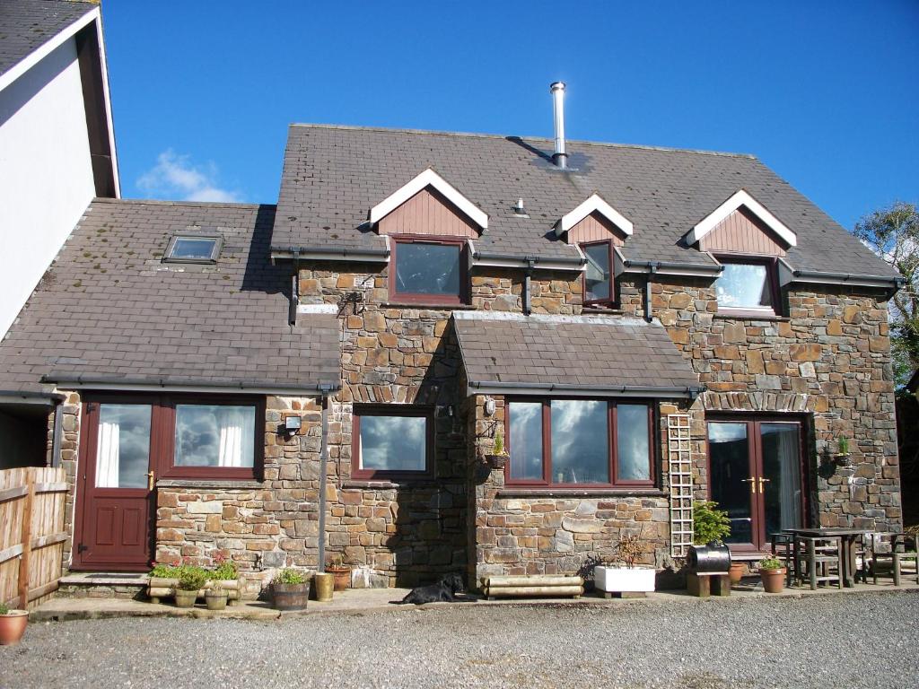 Casa de piedra con puertas y ventanas rojas en Stoke House Bed and Breakfast, en Stoke Rivers