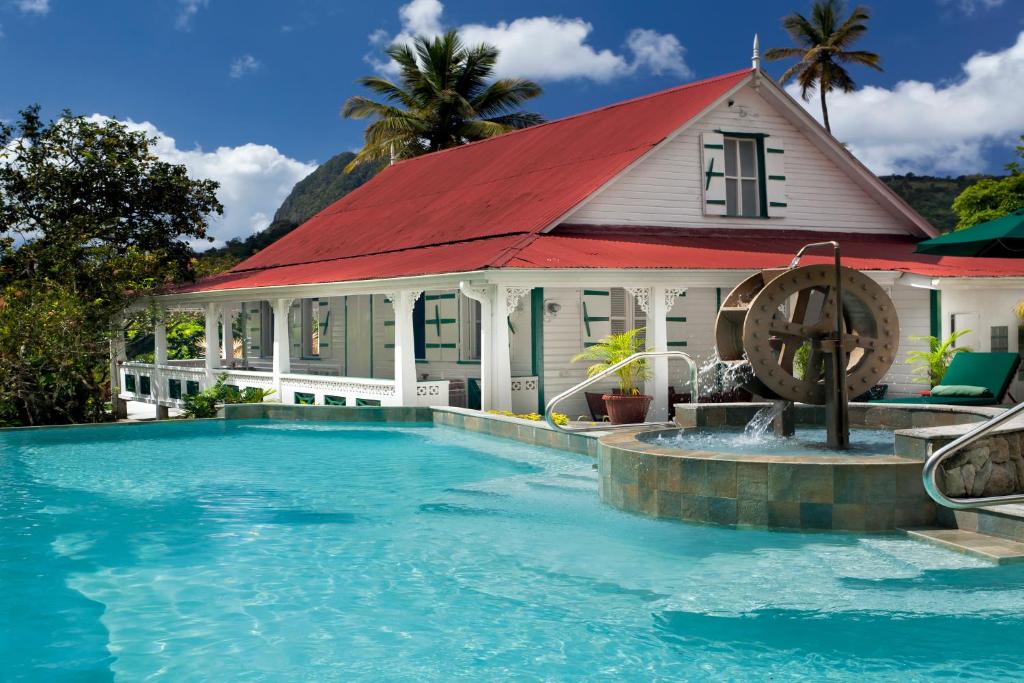 una casa con piscina y techo rojo en La Dauphine Estate, en Soufrière