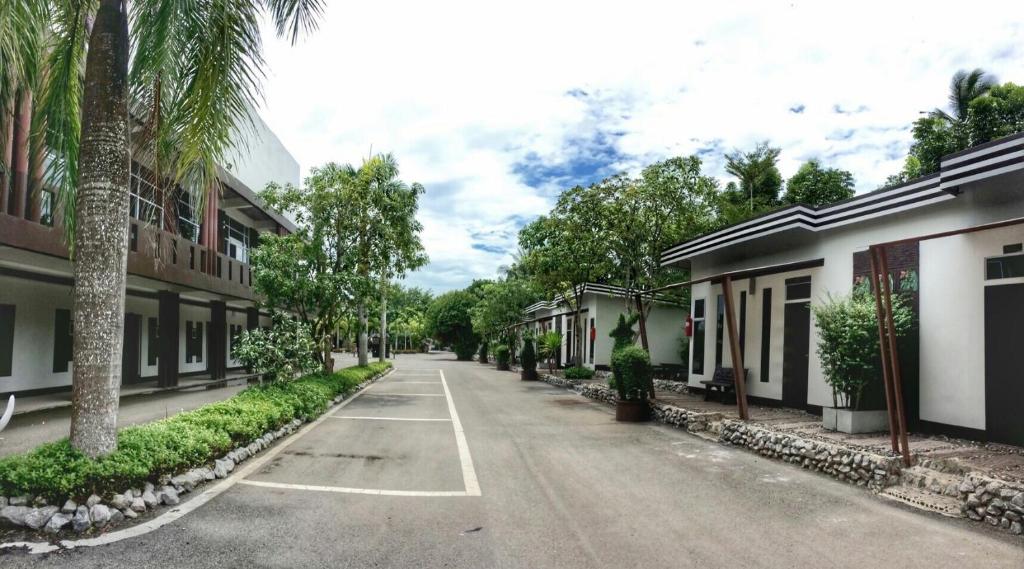 an empty street with palm trees and buildings at River Nature Hotel in Suratthani