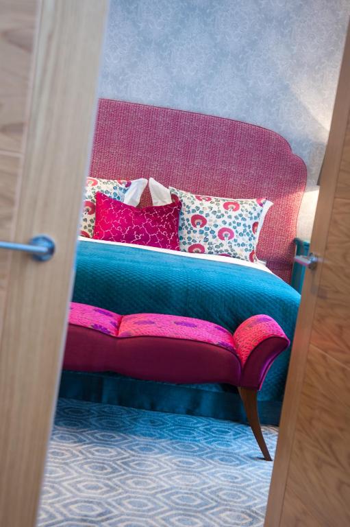 a bedroom with a bed with a pink headboard at Suites at number Ten in Broadstairs