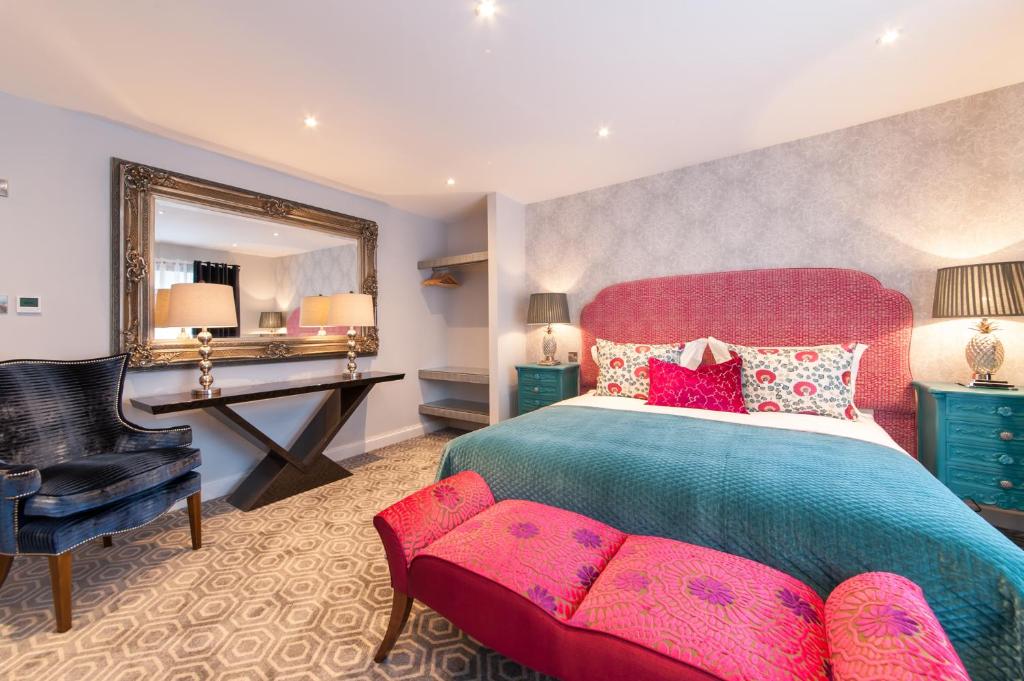 a bedroom with a bed and a chair and a mirror at Suites at number Ten in Broadstairs