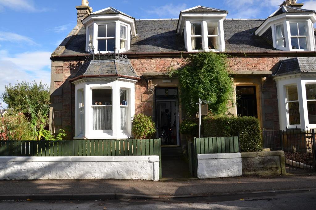 uma casa de tijolos com uma cerca em frente em Averon House em Inverness