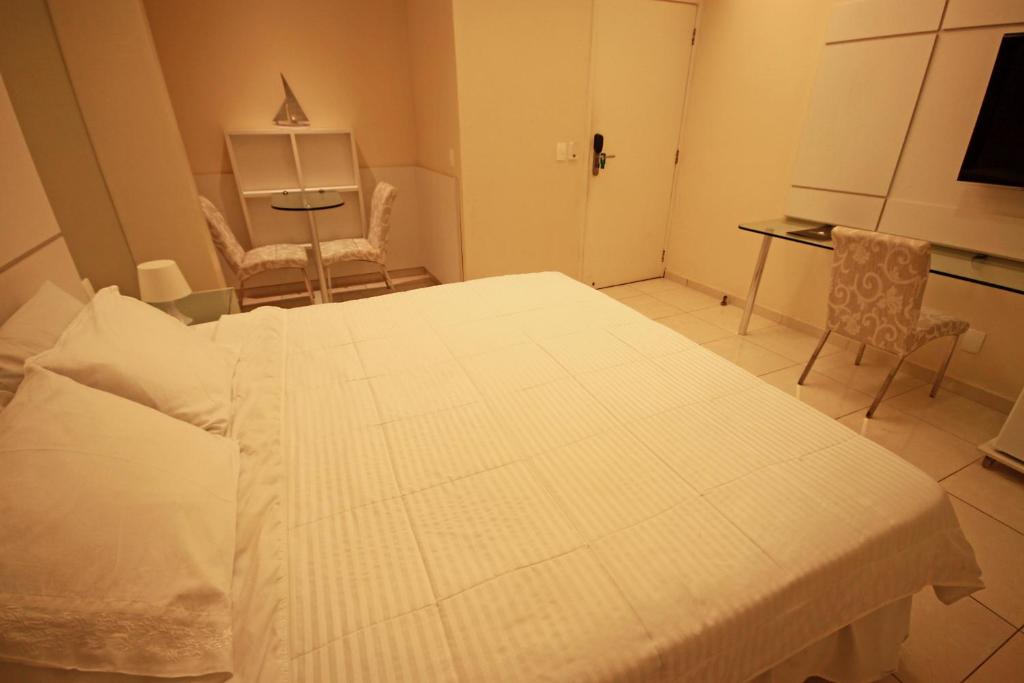 a bedroom with a bed and a table and chairs at Hotel Jangadeiro in Recife