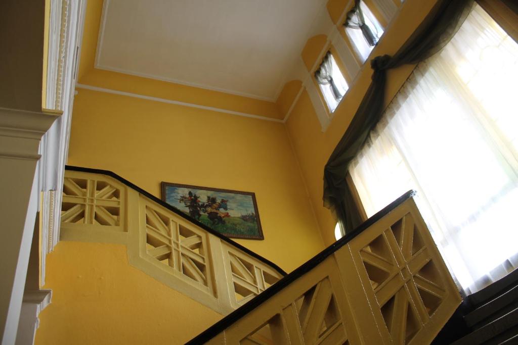 um corredor com paredes amarelas e escadas com uma pintura na parede em Hotel Polonia em Namyslów