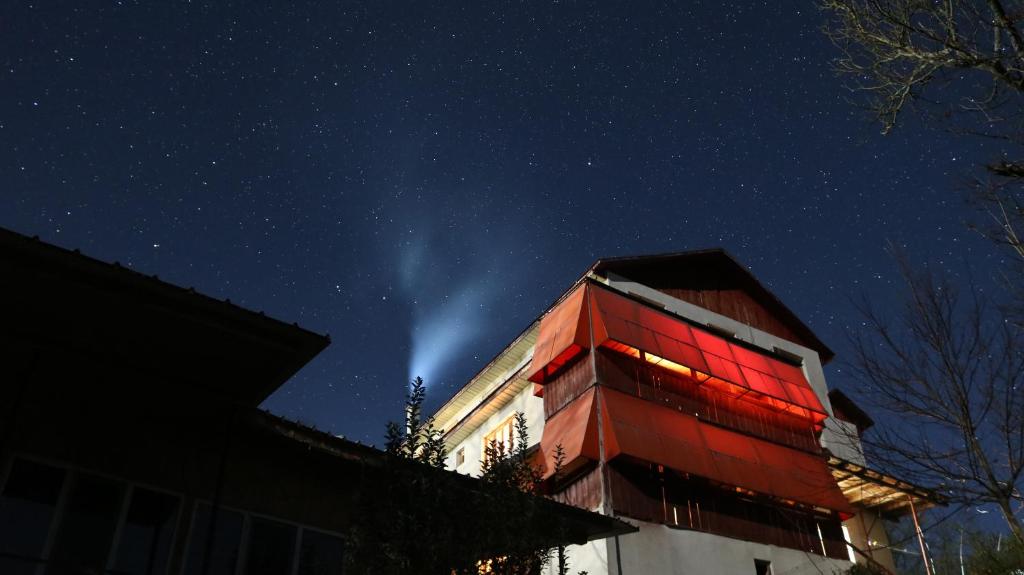 a building with a red facade at night at Pensiunea Tara in Vulcăneasa