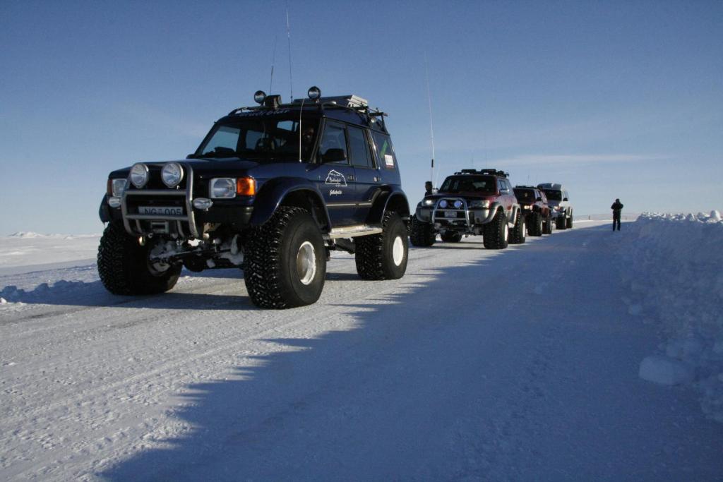a row of trucks driving down a snow covered road at Fjalladýrð Guesthouse in Modrudalur