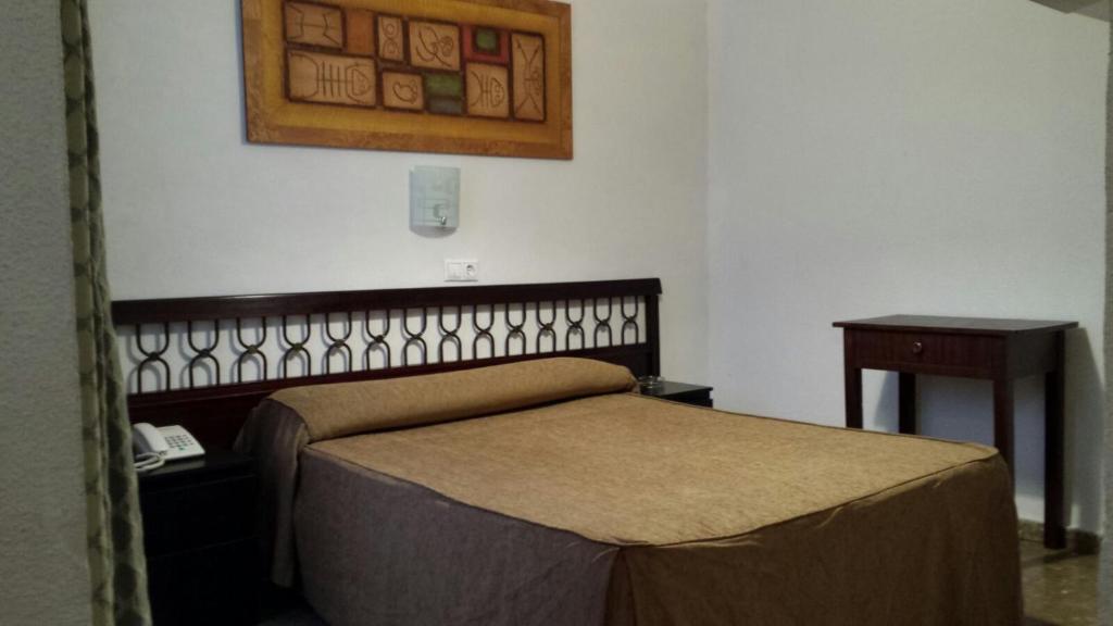 a bedroom with a bed and a phone and a table at Hostal Ronda in Córdoba