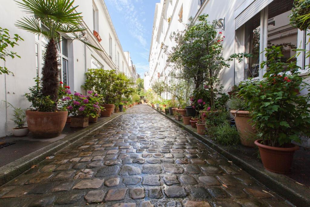 une rue pavée avec des plantes et des bâtiments en pot dans l'établissement Maison Antoinette Paris - MaisonNomadeChic, à Paris