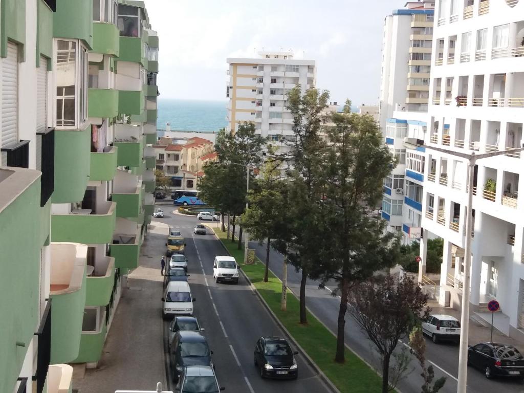 a city street with cars parked on the street between buildings at Alsol in Quarteira