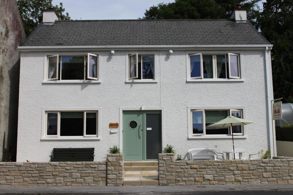una casa blanca con una puerta verde en The Bridges Bed and Breakfast, en Donegal