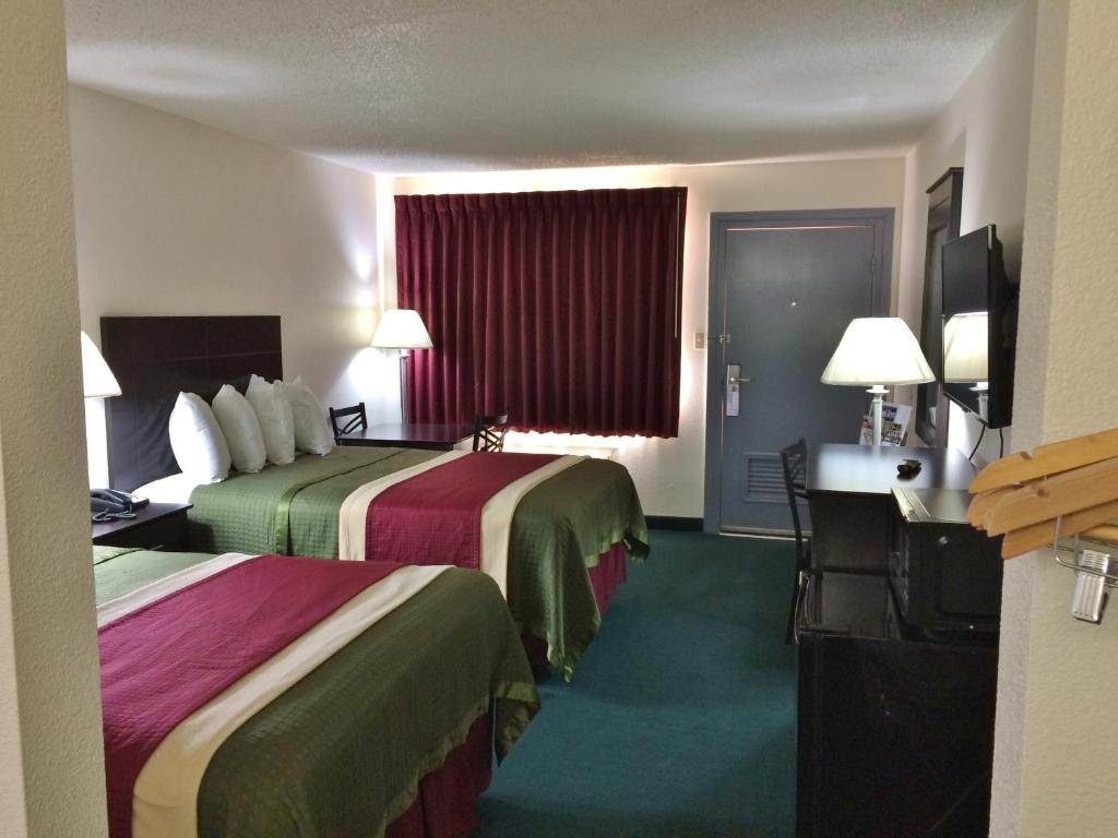 a hotel room with two beds and a desk at Travel Inn & Suites in Atlanta