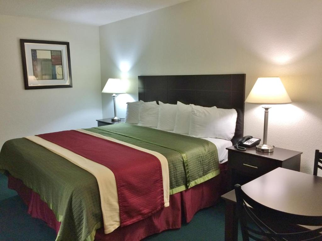 a hotel room with a bed and a table and lamps at Travel Inn & Suites in Atlanta