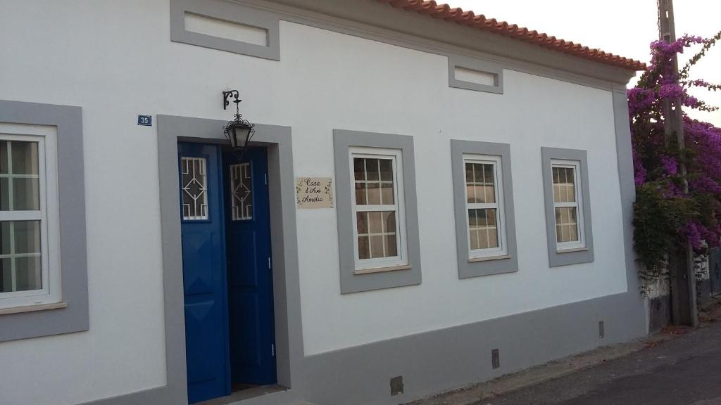 Quinta D'Avó Amélia في Alquerubim: منزل أبيض مع باب ونوافذ زرقاء