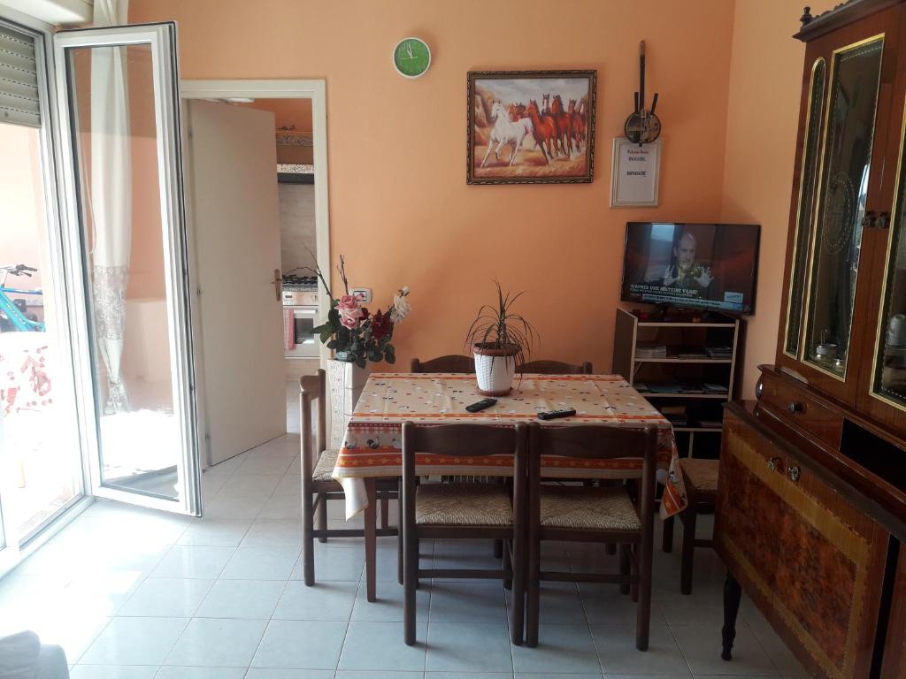 una sala da pranzo con tavolo, sedie e TV di Welcome House a Olbia