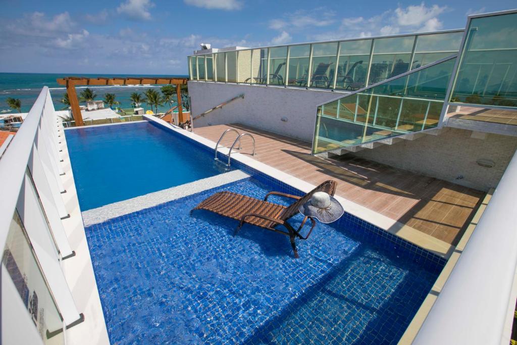 uma piscina com um banco ao lado de um edifício em Baía Branca Porto de Galinhas em Porto de Galinhas