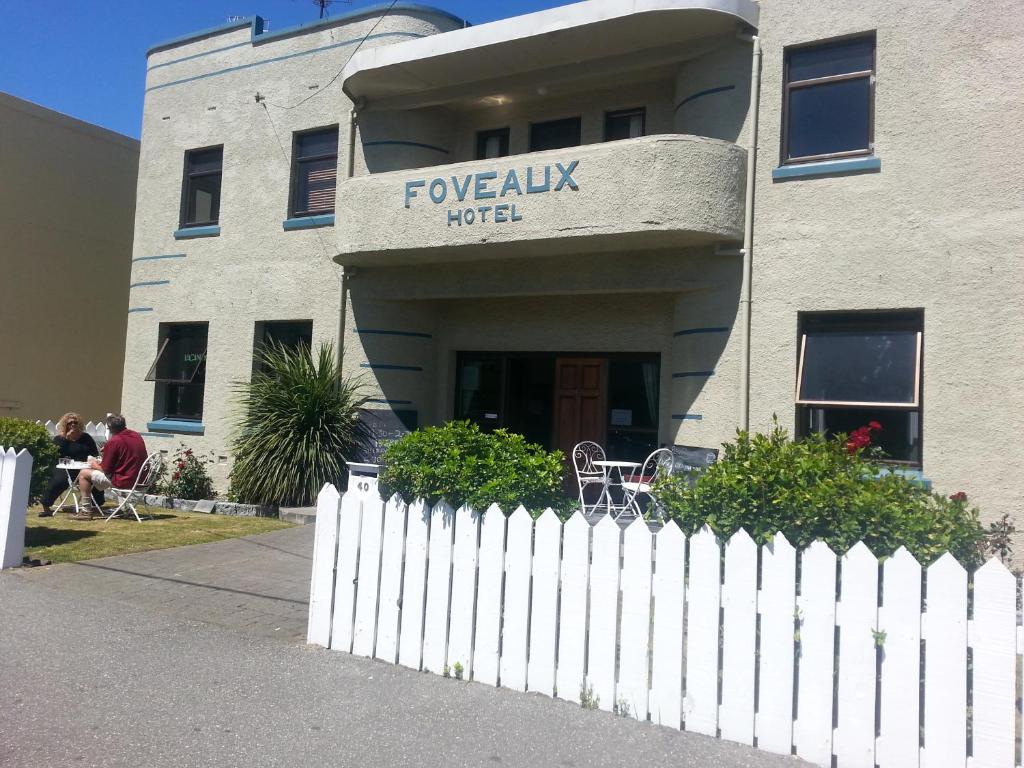 un bâtiment avec une clôture blanche devant un bâtiment dans l'établissement Foveaux Hotel, à Bluff