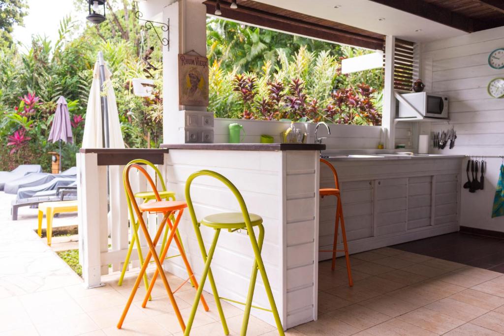 an outdoor kitchen with orange and yellow chairs at Villa Kannel in Petit-Bourg