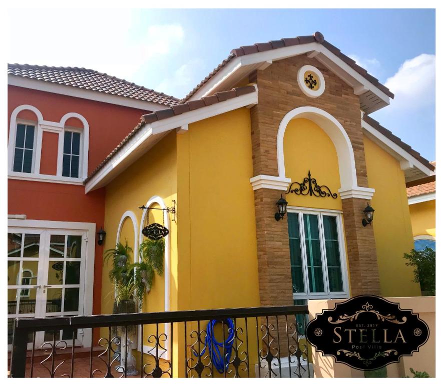 een geel en rood huis met een bord voor bij Stella Pool Villa at Marino khaoyai in Nong Nam Daeng