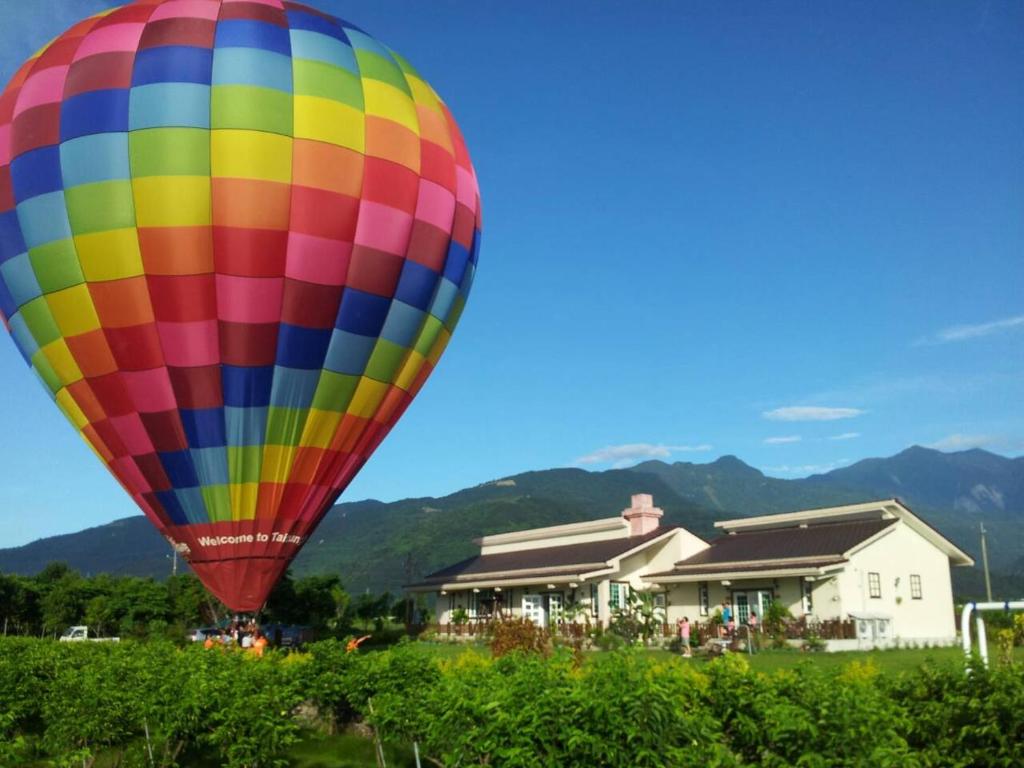a colorful hot air balloon flying over a field at 台東鹿野森活 訂房後來電確認 in Ruiyuan