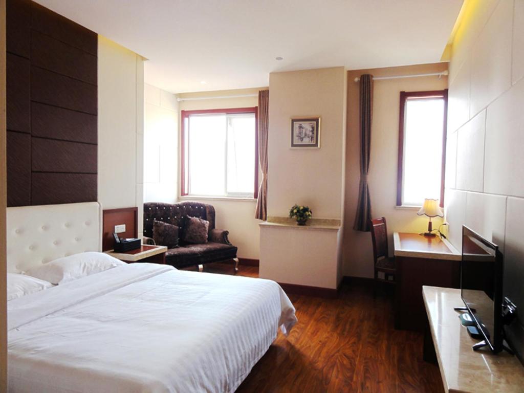青島市にあるQingdao Hua Qi Kaiserdom Hotelの大きなベッドとソファが備わるホテルルームです。