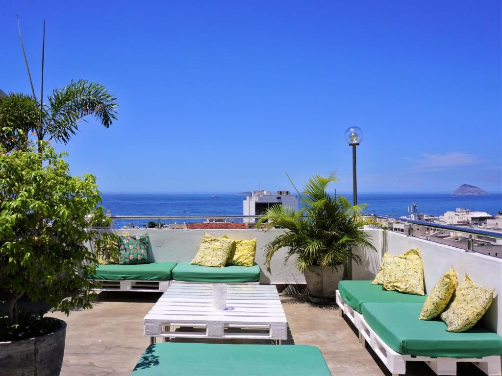 a patio with green and yellow pillows and chairs on a roof at Aquarela do Leme in Rio de Janeiro