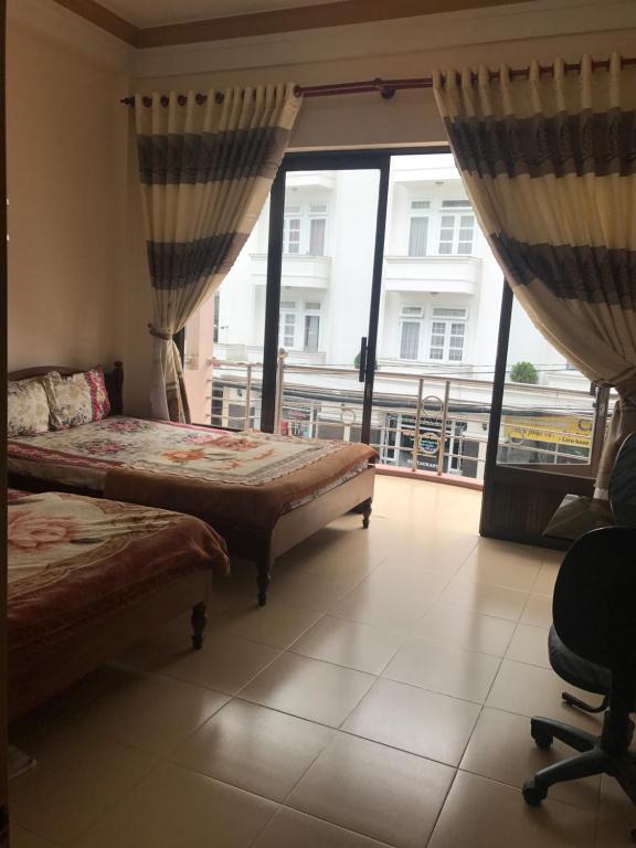 um quarto com 2 camas e uma grande janela em My Anh Guest House em Da Lat