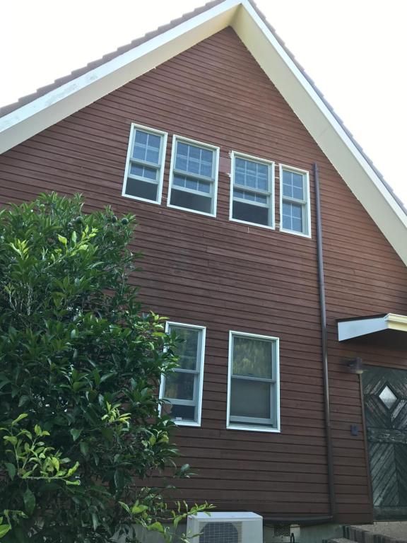 a brown house with white windows and a tree at Guesthouse Irago in Tahara
