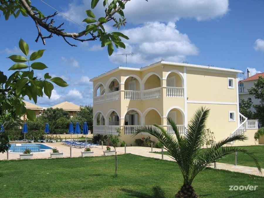 un grand bâtiment jaune avec une piscine et un palmier dans l'établissement Anastasias House, à Laganas