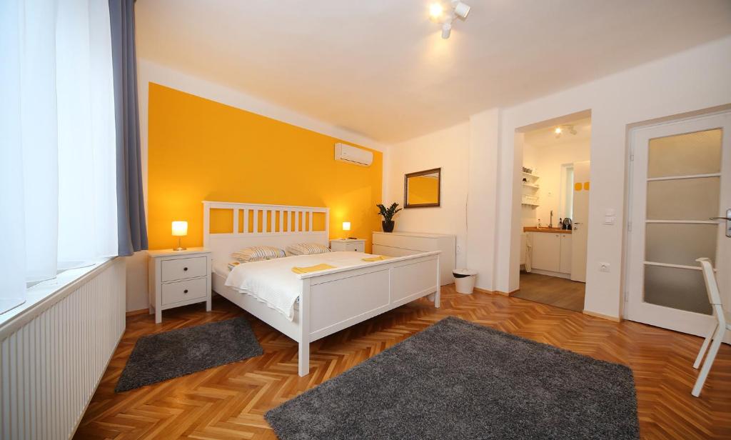 エゲルにあるJadeRoomsのベッドルーム1室(白いベッド1台付)と黄色い壁