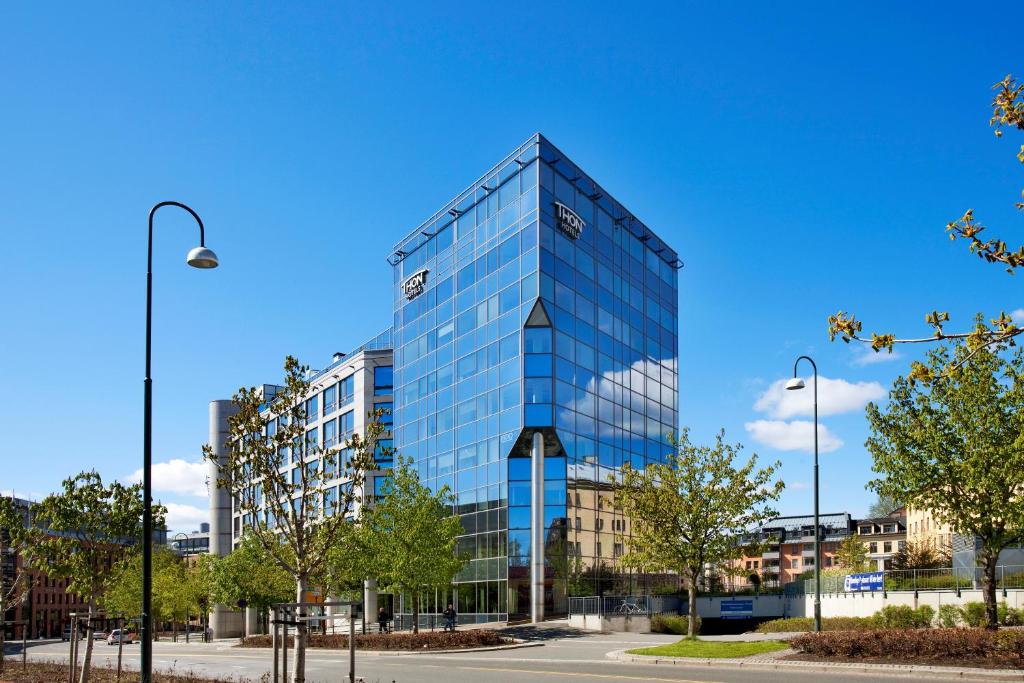 ein Gebäude aus blauem Glas mit Bäumen davor in der Unterkunft Thon Hotel Vika Atrium in Oslo